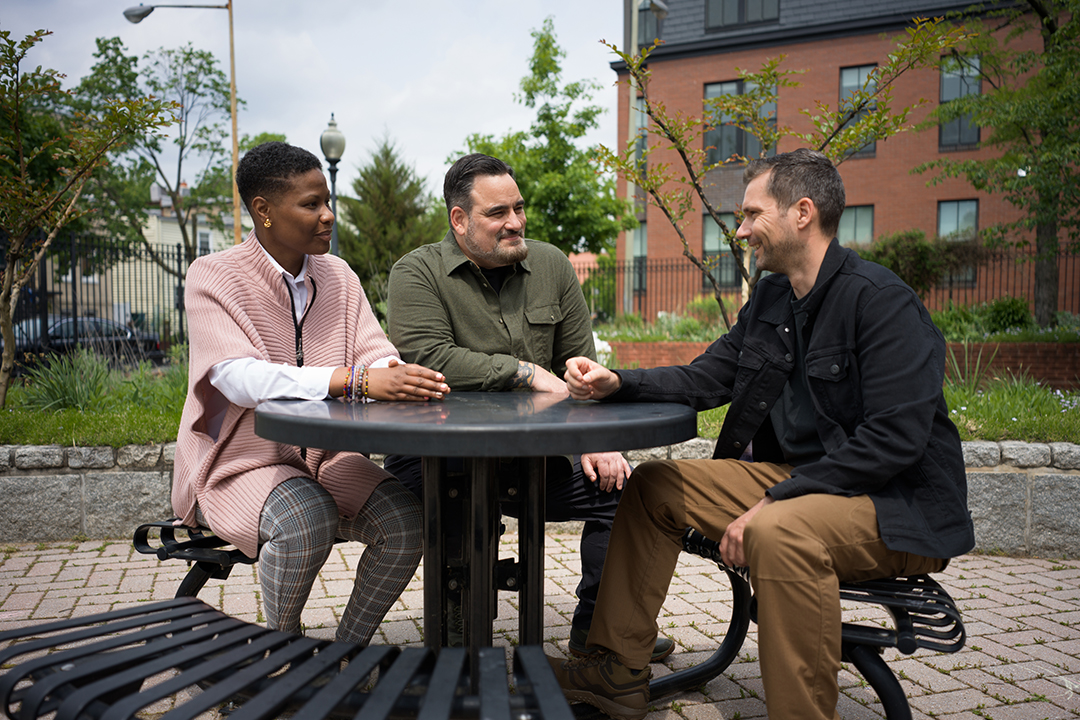 Three Veterans sitting outside at a picnic table talking