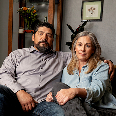 A man with his arm around a women looking at the camera in their living room