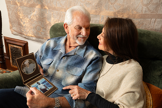 A couple sitting on the couch together looking at old active duty photos