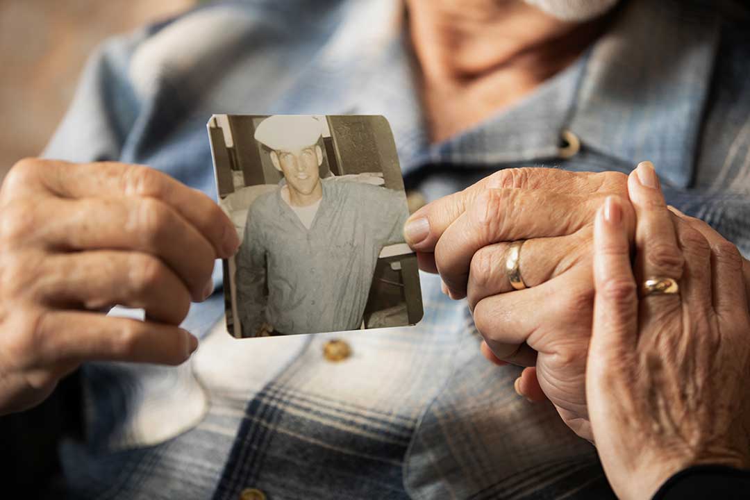 Close-up of Joseph and Margaret's hands holding a photo of Joseph during his service