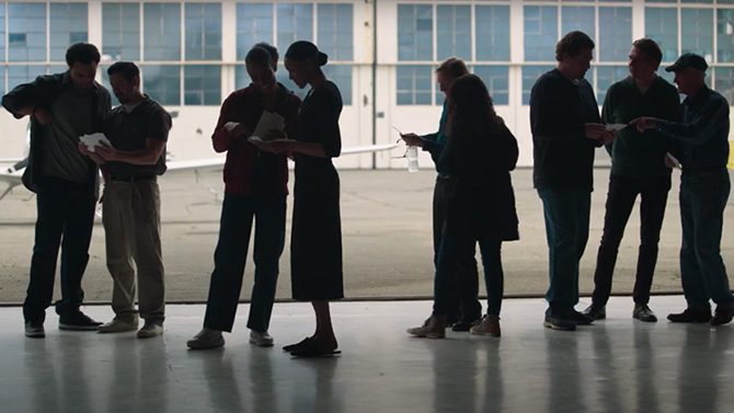 Veterans standing in a warehouse silhouetted in front of large windows