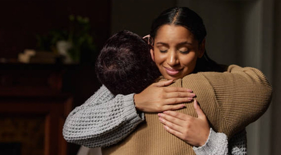 Two women embracing each other with a hug