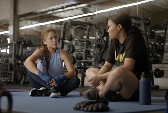 Two women Veterans sit across from each other while talking at the gym