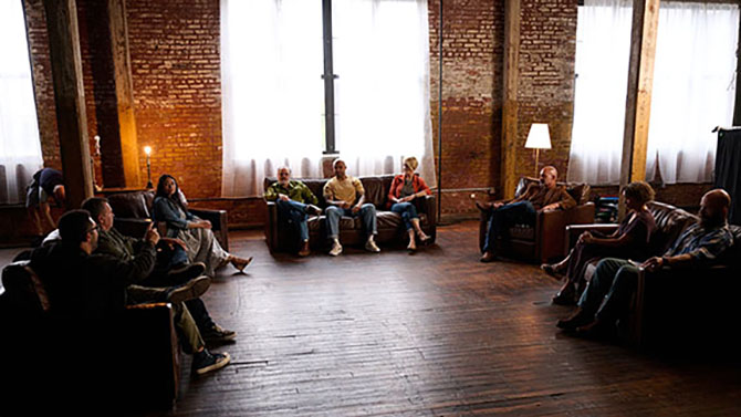 Veterans sitting in dimly lit room on couches having conversations